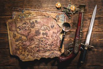 Pirate treasure map on brown wooden table flat lay background.