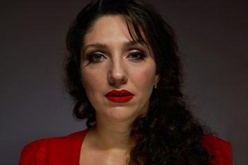 Portrait of young brunette with red lips, black background,