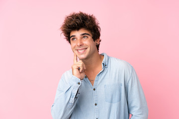 Fototapeta na wymiar Young caucasian man with jean shirt over isolated pink background thinking an idea while looking up
