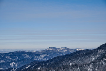 Obraz premium Winter mountain landscape. Snowy mountains overgrown with taiga against a background of gray clouds and blue sky. Russia. Siberia. Altai Republic.