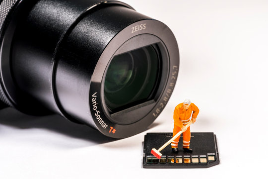 Kleiner Arbeiter mit Besen bereinigt eine Speicherkarte für eine Digitalkamera