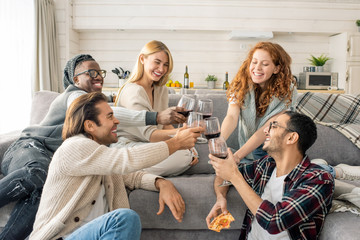 Horizontal shot of cheerful young men and women spending weekend together in cozy apartment...
