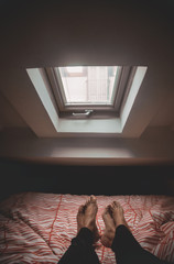 Pies de una pareja en la cama bajo ventana al amanecer. 