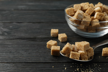 Bowl and spoon with brown sugar on wooden background, close up