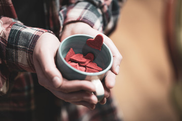 Woman holding cup full of red heart shape figures. Valentine's day concept. Selective focus.