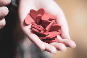 Woman holding a lot of red heart shape figures in hand. Valentine's day concept.
