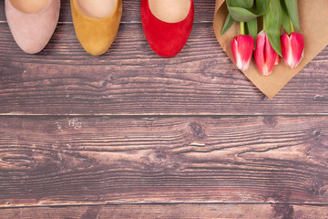 Female high-heeled multicolored shoe with beautiful flowers on wooden background