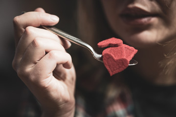 Woman pretending to eat red heart shape figures from the spoon. Selective focus. Valentine's day concept.