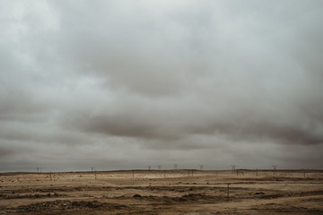 Electricity Pylons in dry desert mountains with dramatic sky