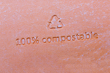 Fototapeta na wymiar 100 % compostable sign or stamp on orange packaging of cosmetics. 100 percent bio recyclable package