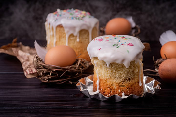 Homemade Easter cake with white icing decorated with eggs on dark background