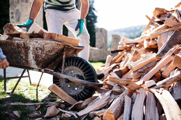 Unrecognizable man outdoors in summer, working with firewood.