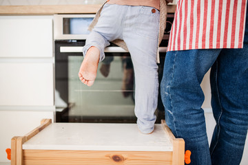 A rear view of small boy with father indoors in kitchen cooking.