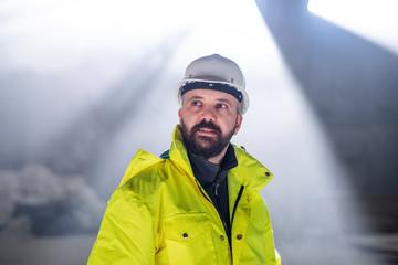 Mature man engineer standing on construction site.
