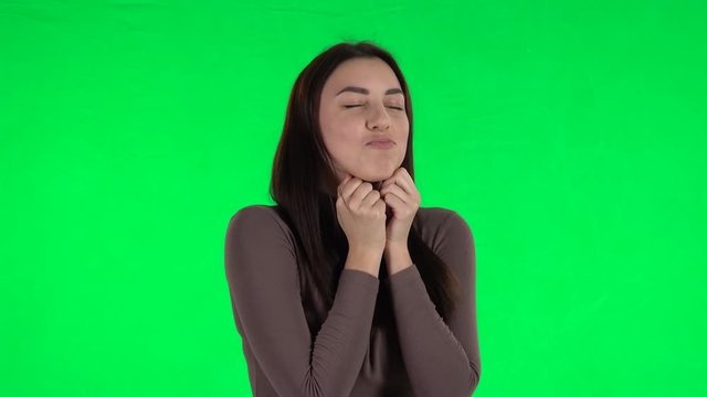 Attractive girl looking with tenderness and folded arms in front of her. Green screen