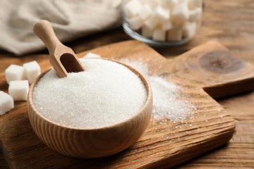 Fototapeta na wymiar Granulated sugar in bowl on wooden table
