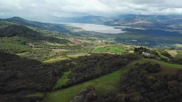 Aerial shot of a beautiful landscape of a lake, surrounded by huge mountains, on a sunny day in Cundinamarca, Colombia. Tomine and guatavita dam. 4k drone.