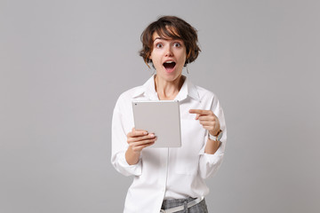 Amazed young business woman in white shirt posing isolated on grey background studio portrait....