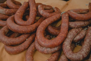 Closeup of kielbasas on top of each other on a wooden table with a blurry background