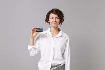 Smiling pretty young business woman in white shirt posing isolated on grey wall background studio...