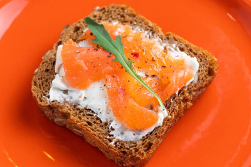 smoked salmon and philadelphia cheese sandwich on rye brown bread with arugula seeds spinach