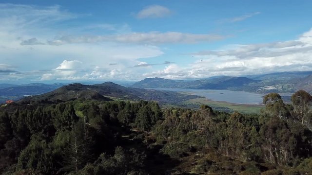 Aerial shot of a beautiful landscape of a lake, surrounded by huge mountains, on a sunny day in Cundinamarca, Colombia. Tomine and guatavita dam. 4k drone.