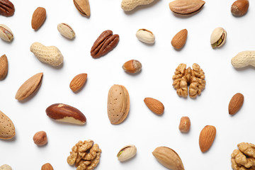 Different delicious nuts on white background, flat lay