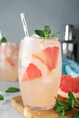 Glass of fresh cocktail with grapefruit on table, closeup