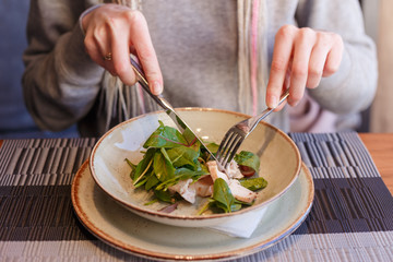 healthy eating, dieting and people concept - close up of young woman hands eating salad in cafe