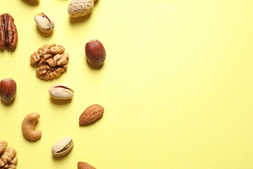 Different delicious nuts on yellow background, flat lay. Space for text