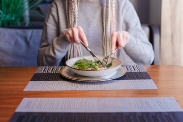 Healthy eating, dieting and people concept - close up of young woman hands eating salad in cafe.
