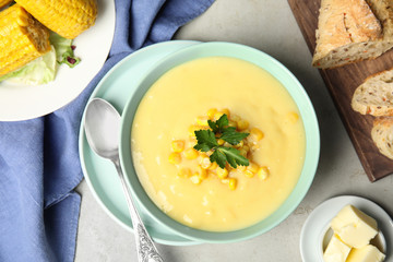 Delicious corn cream soup served on light grey table, flat lay