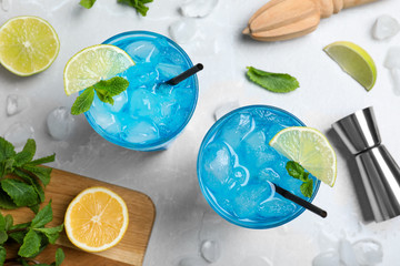 Flat lay composition with Blue Lagoon cocktail on light grey marble table