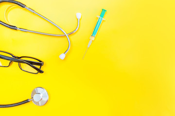 Simply minimal design with medicine equipment stethoscope or phonendoscope glasses and syringe isolated on trendy yellow background. Instrument device for doctor. Health care life insurance concept