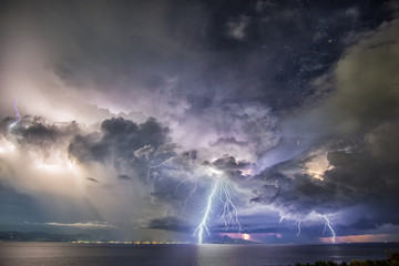 Night time picture of tropical thunder storm with dramatic clouds and lightning striking the sea on...
