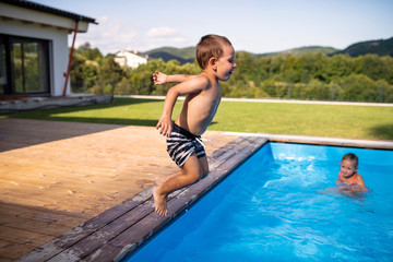 Two small children playing in swimming pool outdoors.