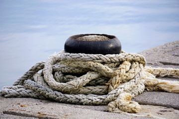 Fototapeta na wymiar Mooring bollards with old, damaged rope tide around it on the marine dock