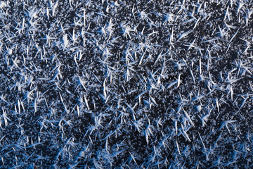 Beautiful macro crystals of white ice on dark icy surface