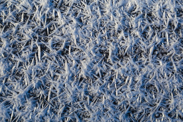 Beautiful macro crystals of white ice on dark icy surface