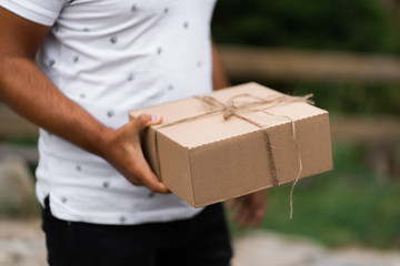 Close-up of man holding gift box with small bow. Unrecognizable successful man presenting Valentines gift. Gift-giving concept. Surprising her..