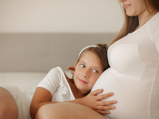 People, family, pareting, pregnant concept. Daughter with pregnant mother is hugging at home