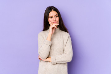 Young caucasian woman isolated on purple background contemplating, planning a strategy, thinking about the way of a business.