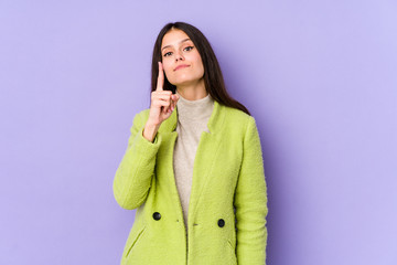 Young caucasian woman isolated on purple background showing number one with finger.
