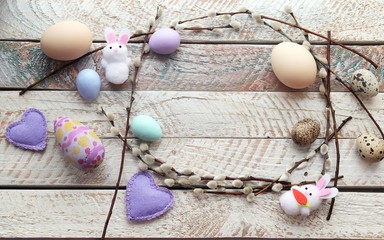 Easter decoration for the holiday, a wreath of eggs, hearts, pussy-willow branches on a bright background, top view