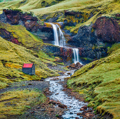 Beautiful midnight sun view of nameless waterfall on Rauda river. Vivid green hills on the southern...