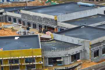 Construction of a one-story comfortable modern new monolithic frame building of a shopping center within walking distance in a new area. View from above