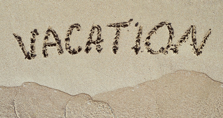 Vacation written on sand.