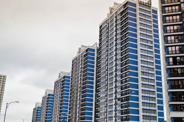 Fototapeta premium New modern tall blue glass multi-storey comfortable urban monolithic frame houses buildings skyscrapers new buildings in the big city of the megalopolis