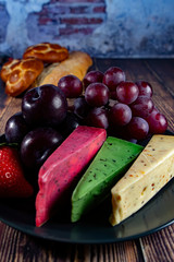 Different Dutch cheese types on plate and bread and fruit in the background