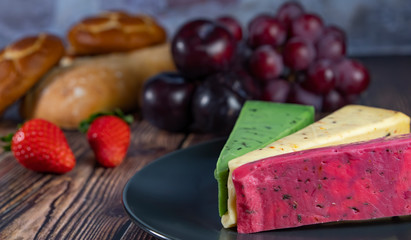 Different Dutch cheese types on plate and bread and fruit in the background